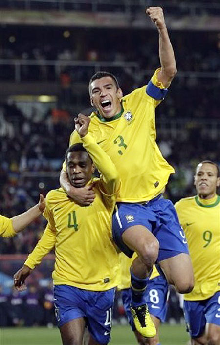 Brazil's Juan, left, celebrates with Brazil's Lucio, top, and Brazil's Luis Fabiano after scoring the opening goal during the World Cup round of 16 soccer match between Brazil and Chile at Ellis Park Stadium in Johannesburg, South Africa, Monday, June 28, 2010
